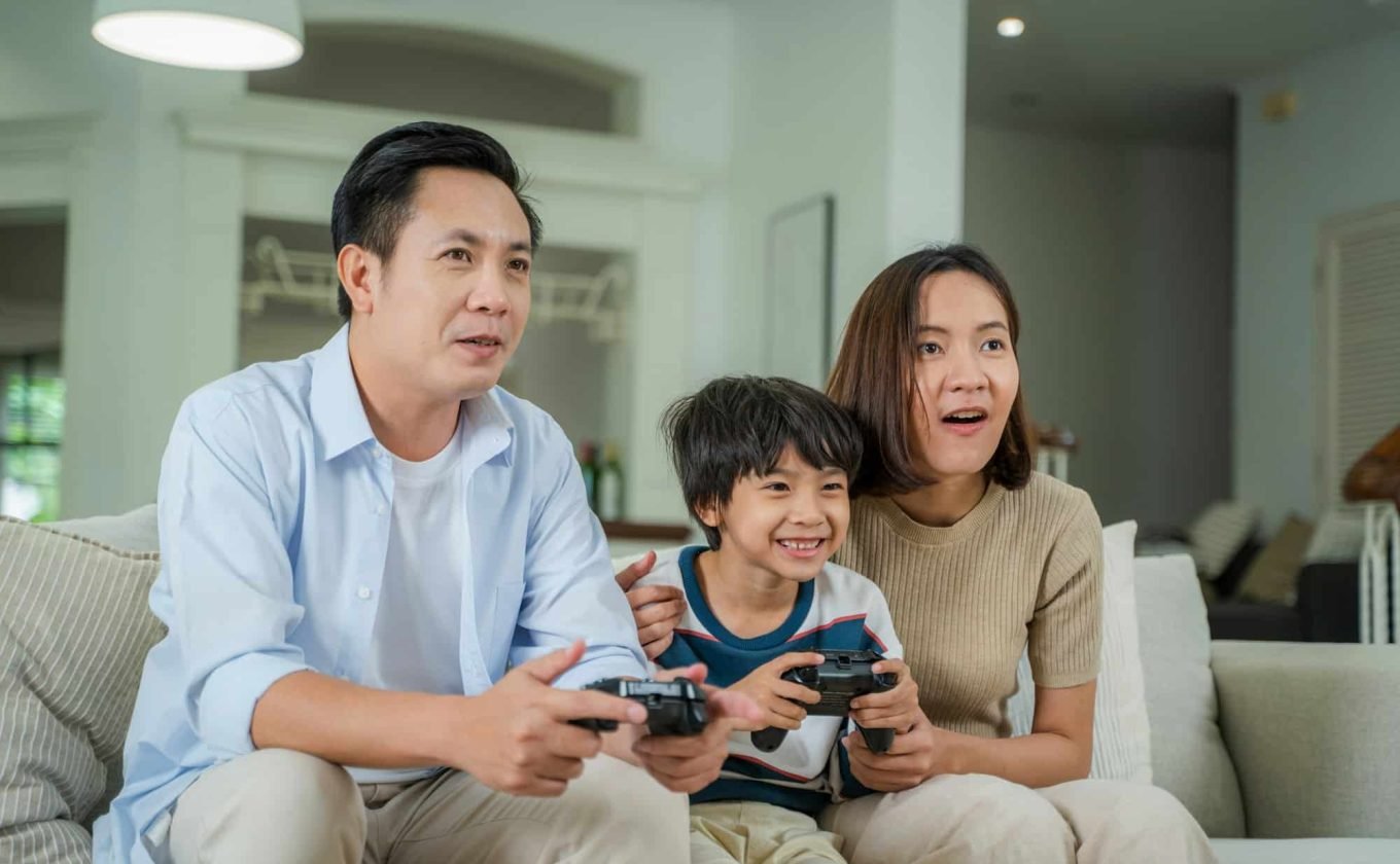 Family sitting on the couch together playing video games.