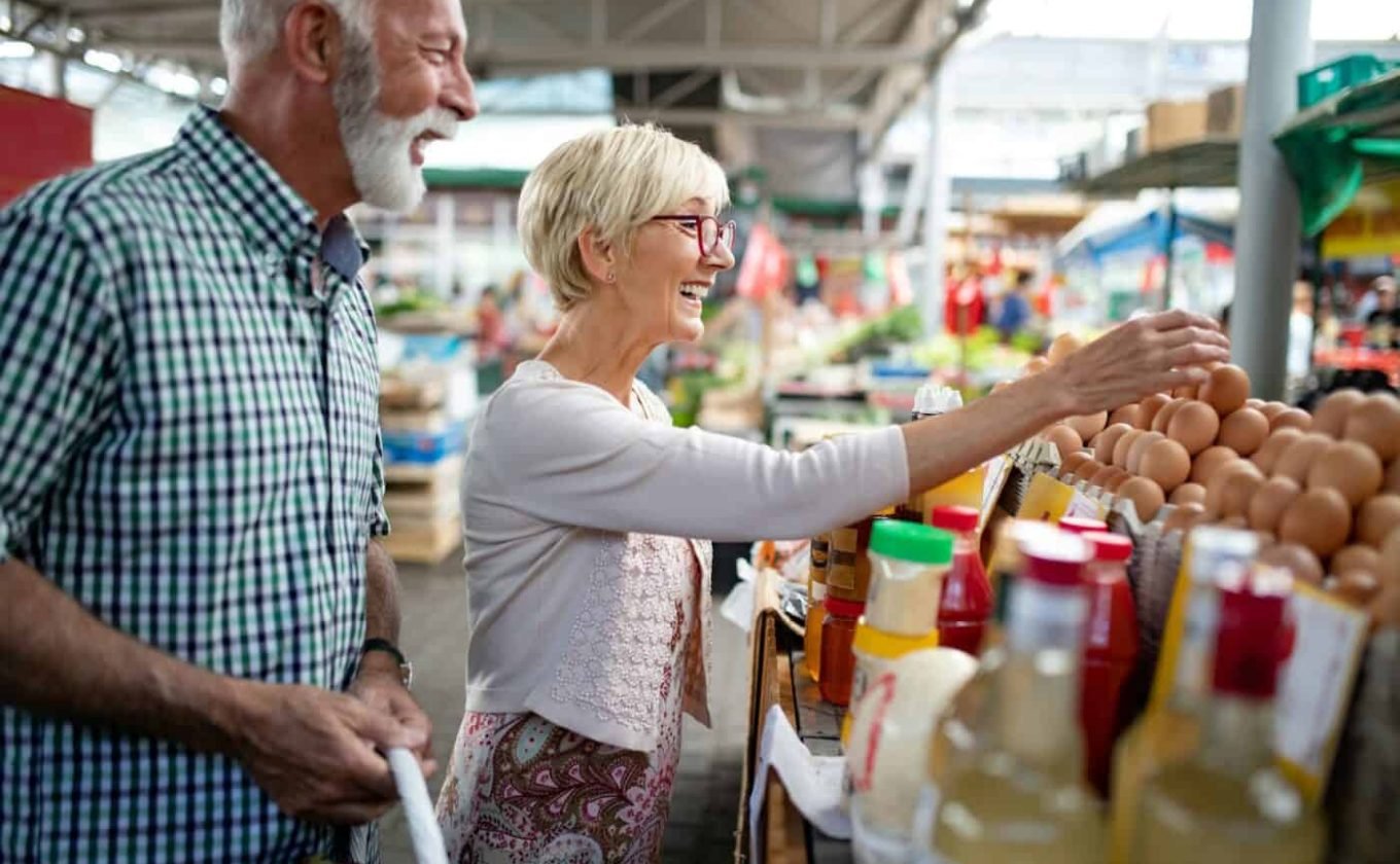 Happy senior couple with basket at the local market