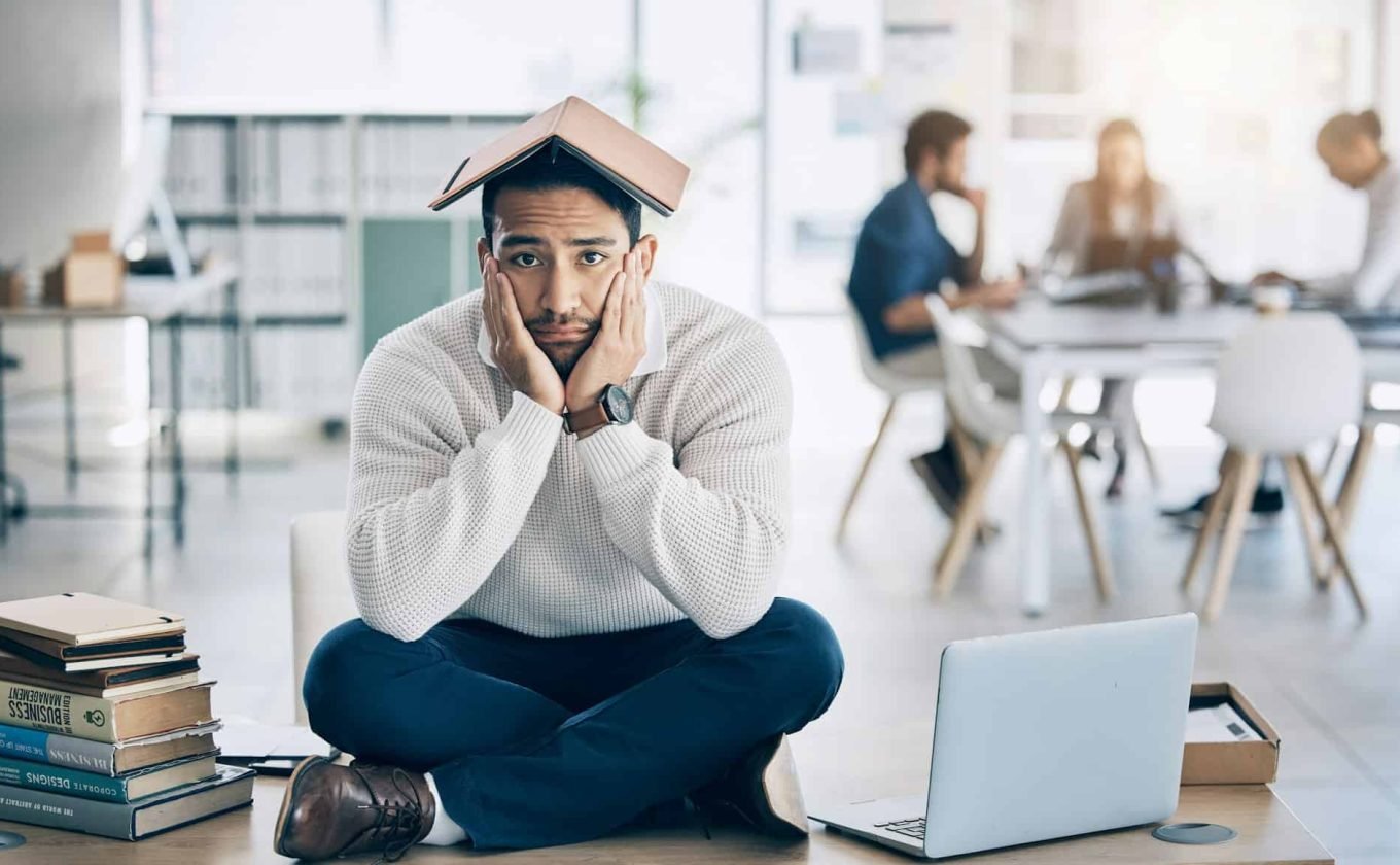 Laptop, books and businessman in training fail, burnout and stress with overwhelm workload in offi